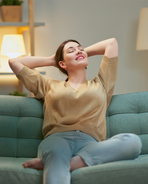 Eine junge braunhaarige Frau entspannt auf einer Couch. (Foto)