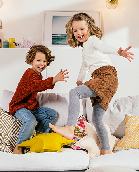 Zwei Kinder springen auf einem Sofa (Foto)